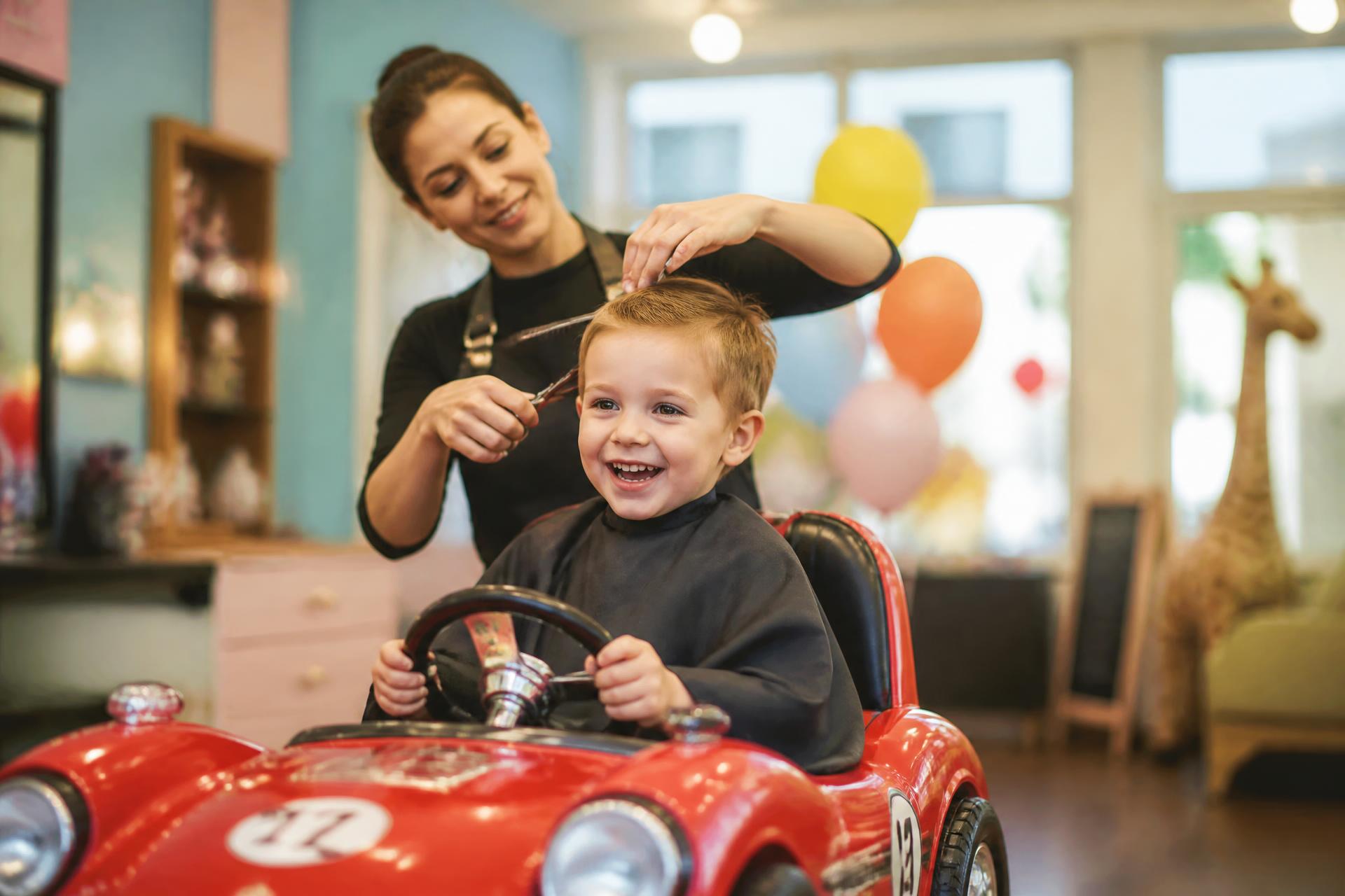 Criança feliz recebendo corte com cuidado e atenção no Looky